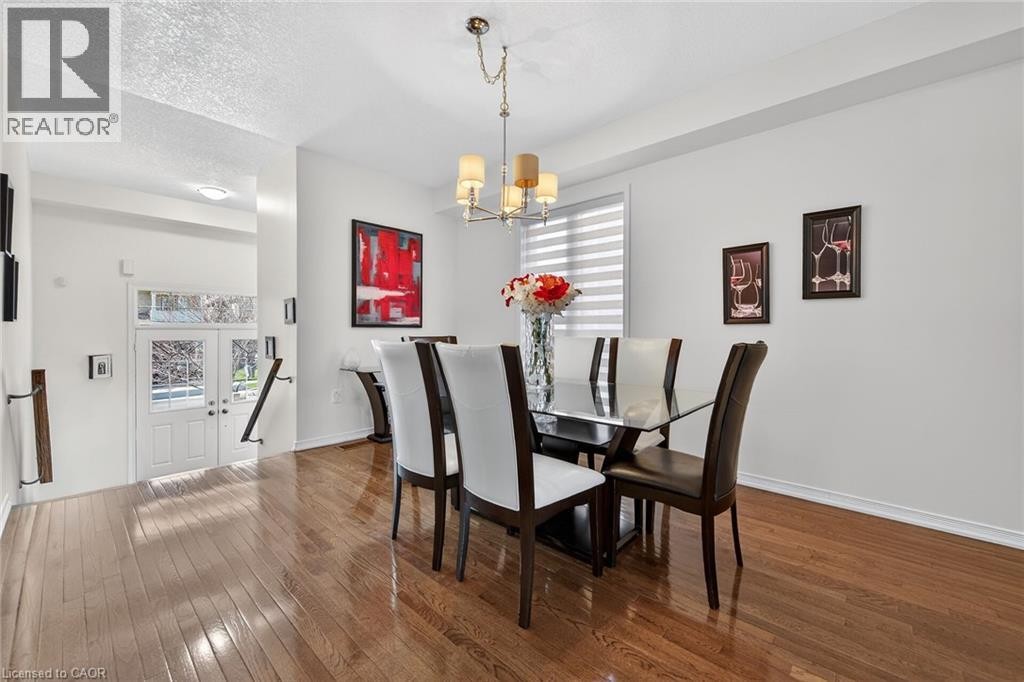 Dining room with dark wood-style floors, hanging lights, and a textured ceiling - 97 Sirente Drive, Hamilton, ON