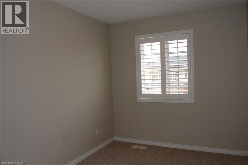 Window with white plantation shutters, neutral tone wall paint, and carpeting - 507 Beaumont Crescent, Kitchener, ON
