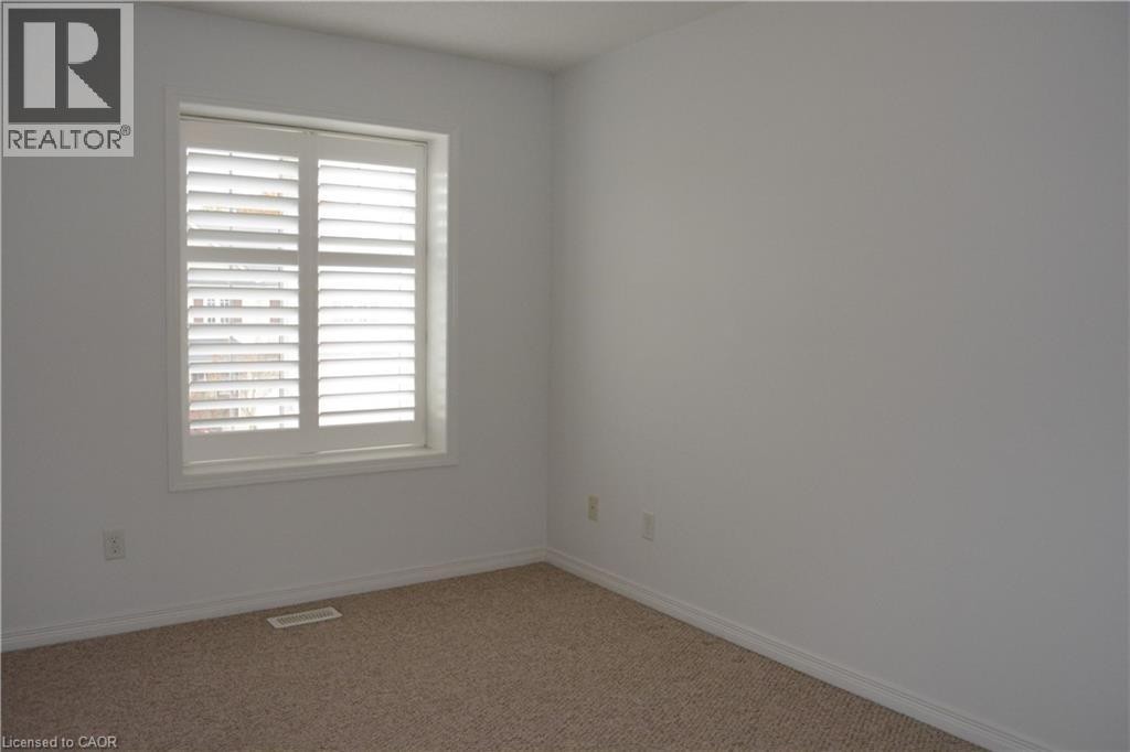 Neutral wall paint, carpeted flooring, and a window with plantation shutters - 507 Beaumont Crescent, Kitchener, ON