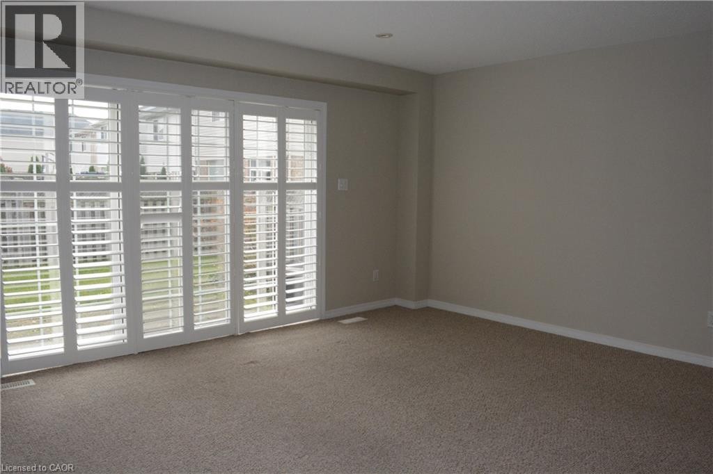 Sliding glass door with white plantation shutters, neutral-toned carpeting, and recessed ceiling lighting - 507 Beaumont Crescent, Kitchener, ON