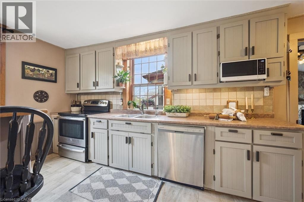 Kitchen featuring paneled cabinetry, stainless steel appliances, dual basin sink, and tile backsplash - 630 Robert Ferrie Drive, Kitchener, ON