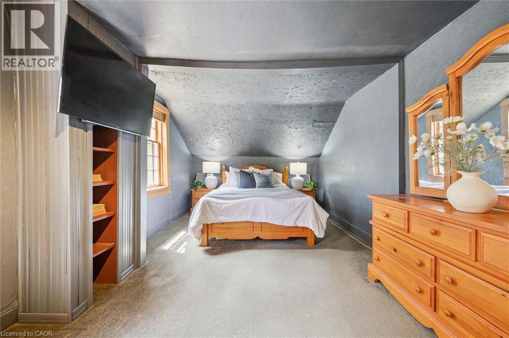 Sloped ceiling room featuring carpet flooring, natural wood-finish window trim, and a built-in shelving unit - 630 Robert Ferrie Drive, Kitchener, ON