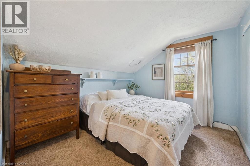 Sloped ceiling room featuring carpet flooring, built-in shelving, and a double-hung window with wood trim - 630 Robert Ferrie Drive, Kitchener, ON