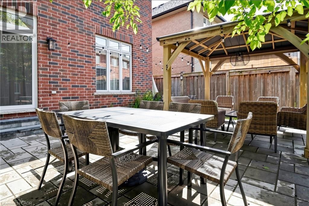 Paver patio featuring a wooden gazebo with a pitched roof, brick exterior, and privacy fencing - 173 Raymond Road, Ancaster, ON