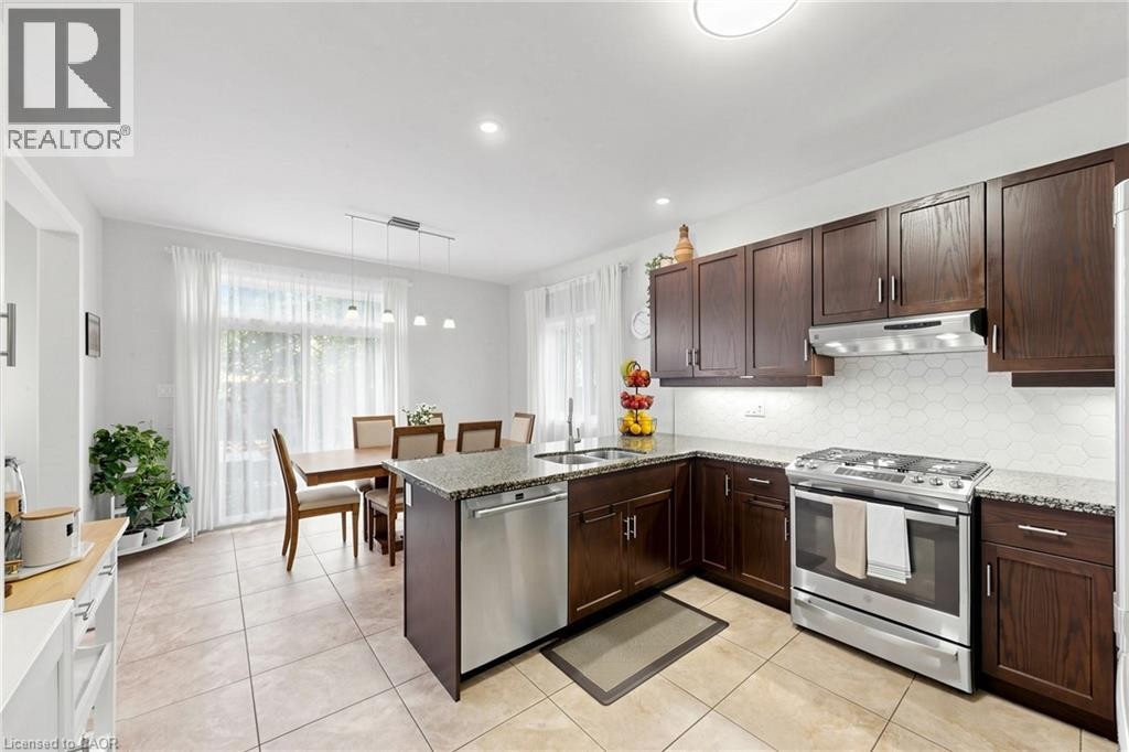 Kitchen featuring dark wood cabinetry, stainless steel appliances, speckled countertops, and a hexagonal tile backsplash - 173 Raymond Road, Ancaster, ON
