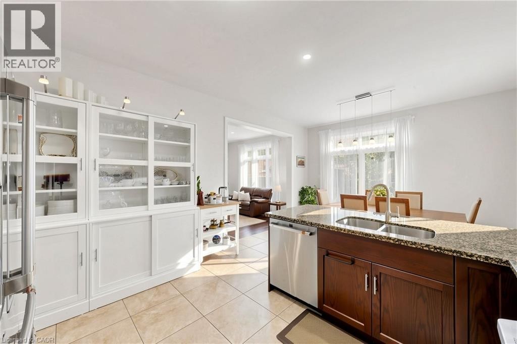 Kitchen featuring a central island with dual sinks, built-in dishwasher, and stone countertop - 173 Raymond Road, Ancaster, ON