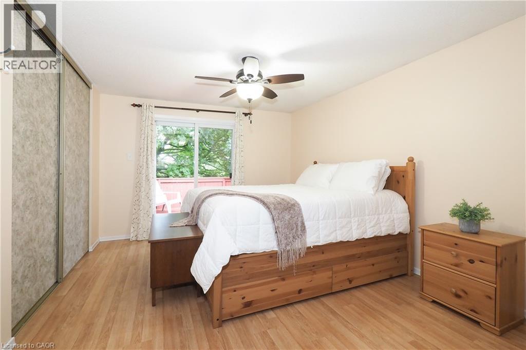 Wood-finish flooring, sliding glass door to exterior balcony, ceiling fan with integrated lighting, and sliding closet doors - 219 Foxhunt Road, Waterloo, ON