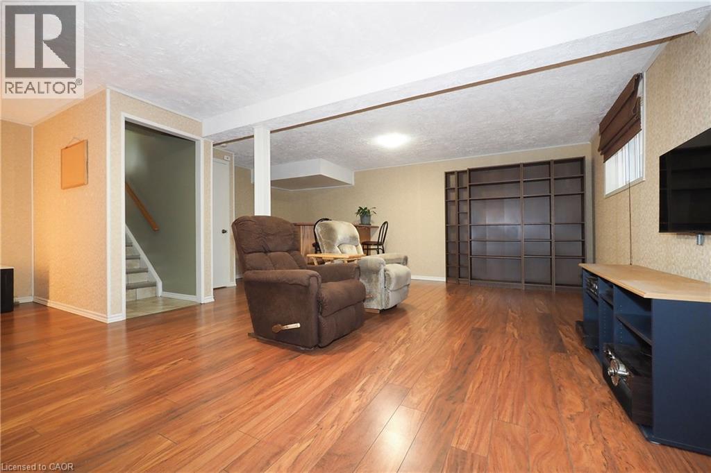 Wood-finish flooring throughout, featuring a built-in shelving unit, recessed lighting, and a window with blinds - 219 Foxhunt Road, Waterloo, ON
