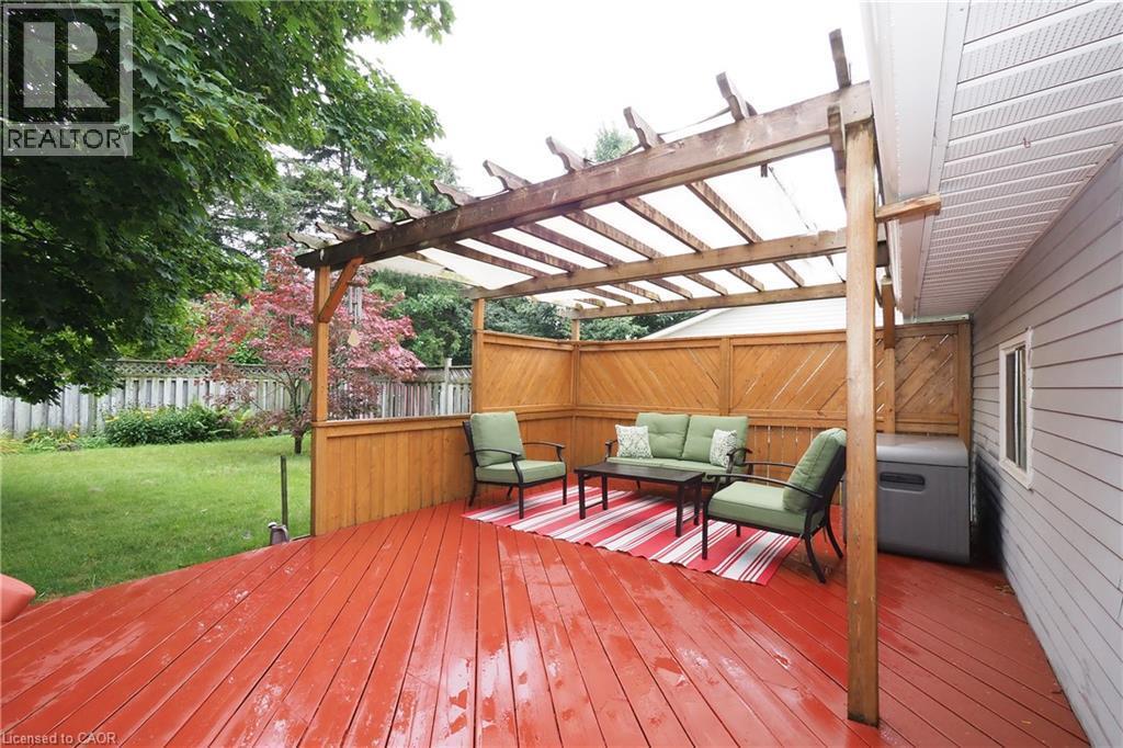 Expansive wood deck with a red finish, featuring a pergola with a translucent cover and privacy fencing - 219 Foxhunt Road, Waterloo, ON