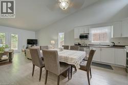 Combined kitchen and dining area featuring white cabinetry, light wood-finish flooring, and a vaulted ceiling - 