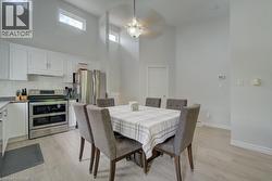 Kitchen and dining area featuring vaulted ceilings with high transom windows, white cabinetry, a subway tile backsplash, and stainless steel appliances - 