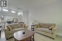 Open-concept living area with wood-finish flooring, a vaulted ceiling, and high horizontal windows - 