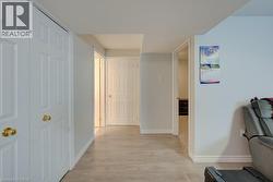 Hallway with wood-finish flooring, white paneled doors, and light wall tones - 