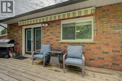 Expansive wood-finish deck featuring a brick exterior and sliding glass doors - 