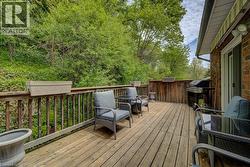 Spacious wood deck with ample room for outdoor entertaining, featuring a sliding glass door for interior access, brick exterior, and a striped retractable awning - 