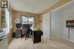 Bright interior room featuring light wood-finish flooring, two windows, and a white paneled door - 