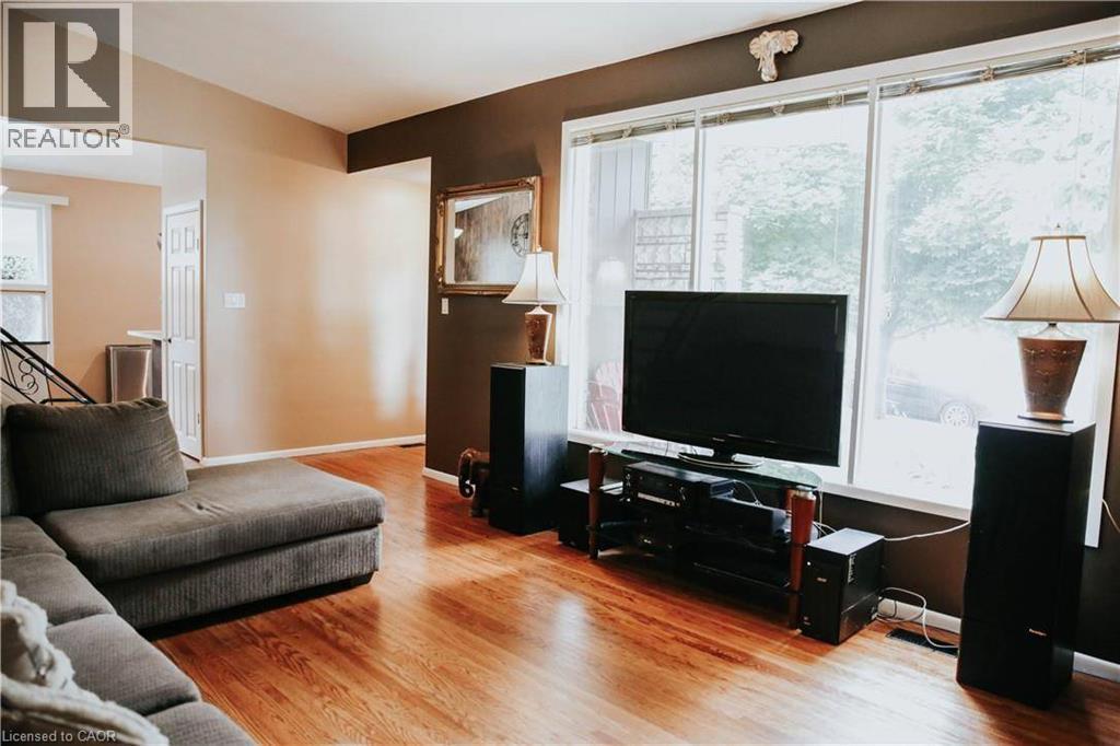 Hardwood-finish flooring, large window with white trim, framed mirror, and warm-toned wall finishes - 1 Vera Court, Hamilton, ON