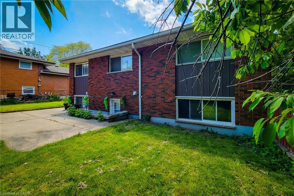 Brick exterior with a concrete driveway and lush green lawn - 1 Vera Court, Hamilton, ON