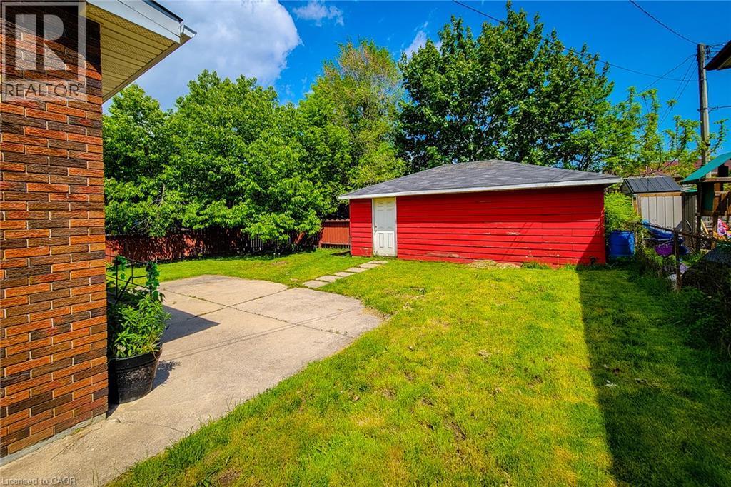 Red exterior outbuilding with a white entrance door, surrounded by a grassy area and concrete path - 1 Vera Court, Hamilton, ON