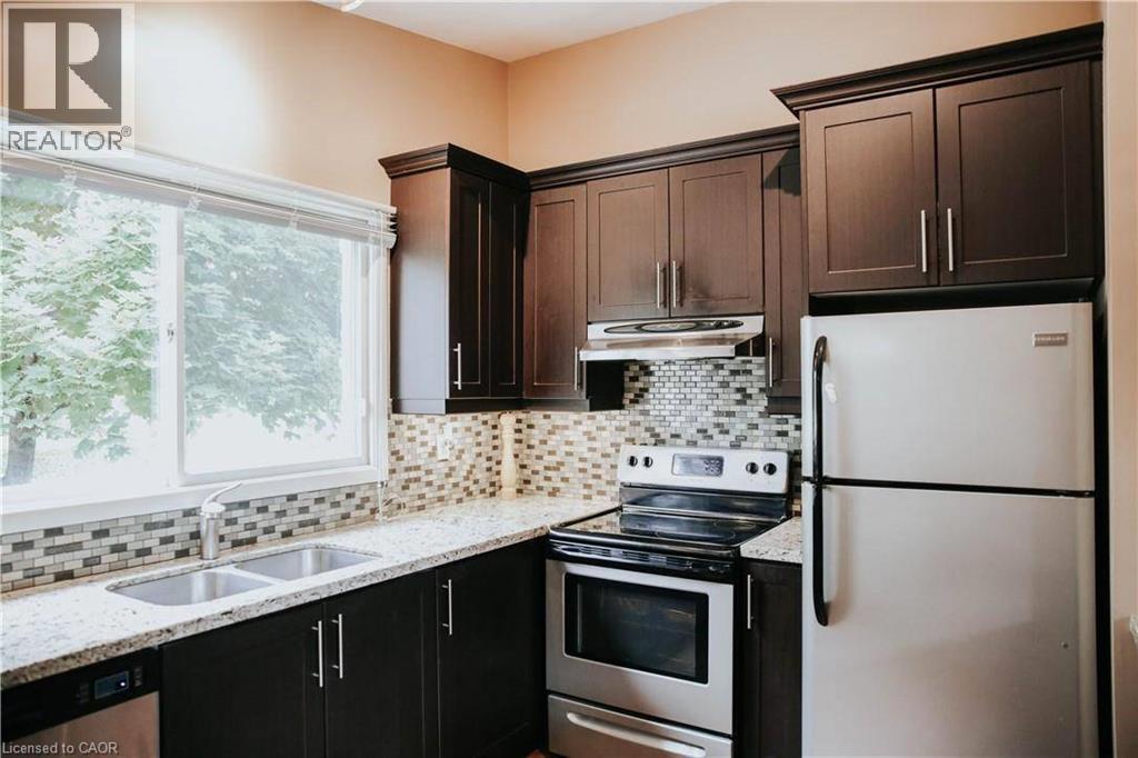 Kitchen featuring dark wood-finish cabinetry, light speckled countertops, a mosaic tile backsplash, and stainless steel appliances - 1 Vera Court, Hamilton, ON