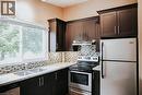 Kitchen featuring dark wood-finish cabinetry, light speckled countertops, a mosaic tile backsplash, and stainless steel appliances - 1 Vera Court, Hamilton, ON 