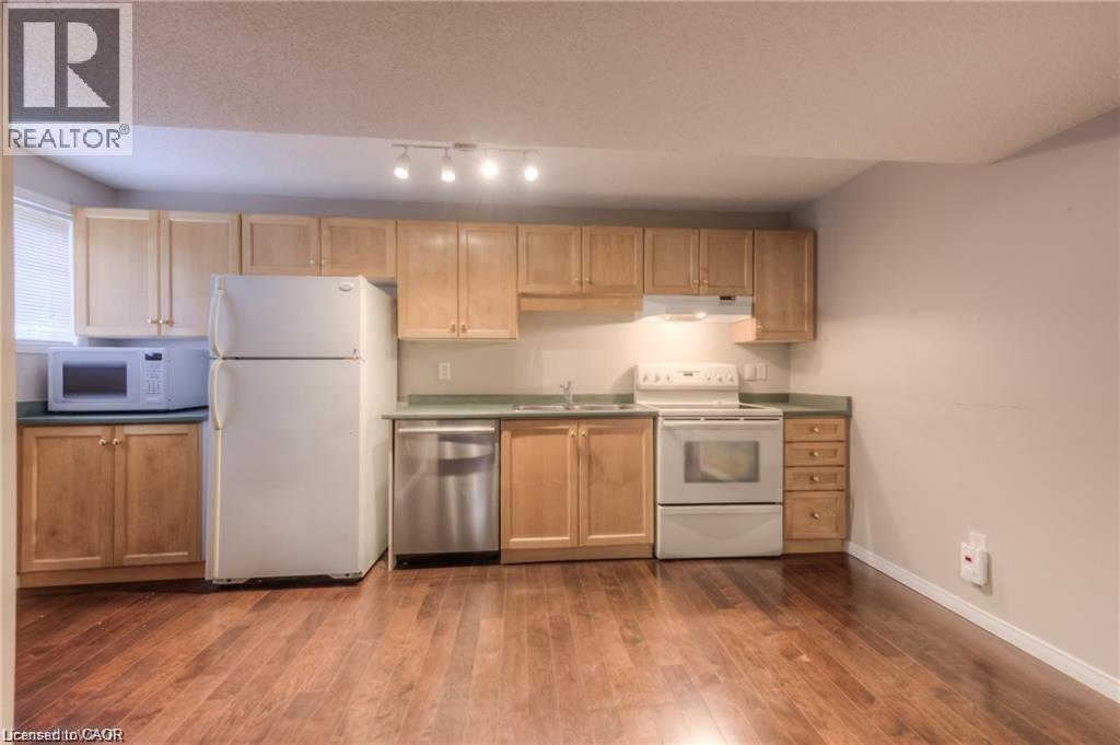 Kitchen featuring wood-finish flooring, light wood cabinetry, green countertops, and white appliances - 8 Melran Drive Unit# 2, Cambridge, ON