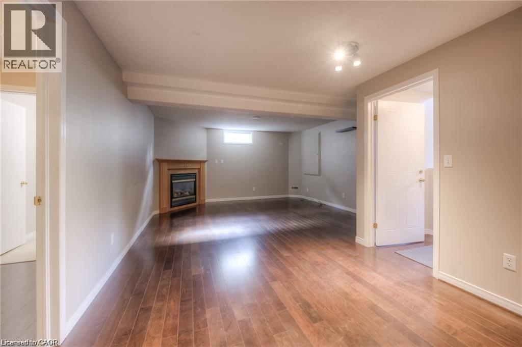 Wood-finish flooring, corner fireplace with wood mantel, neutral wall tones, recessed lighting, and white trim - 8 Melran Drive Unit# 2, Cambridge, ON