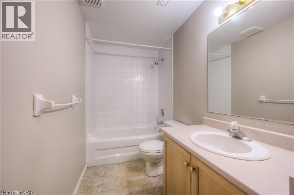 Bathroom featuring a tub/shower combination with white subway tile surround, a light-toned vanity with an integrated sink, a large wall-mounted mirror, and a neutral color palette - 8 Melran Drive Unit# 2, Cambridge, ON
