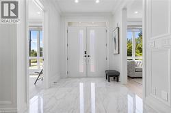 Grand entry foyer featuring polished marble-finish flooring and a double-door entryway with frosted glass inserts - 