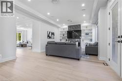 Spacious living area featuring light wood-finish flooring, recessed lighting, and crown molding - 