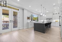 Spacious kitchen featuring light wood-finish flooring, white cabinetry, and a dark gray island with countertop seating - 
