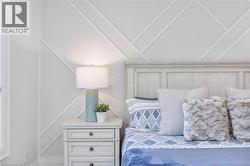 Geometric accent wall paneling with a light wood-finish headboard, complemented by a distressed wood-finish nightstand featuring three drawers and dark hardware - 