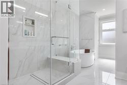Glass-enclosed shower with a built-in bench, recessed niche, and linear drain - 