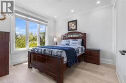 Bright room featuring large triple windows, light wood-finish flooring, recessed lighting, crown molding, and white baseboards - 