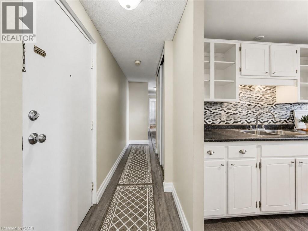 Kitchen featuring white cabinetry, dark countertops, and a mosaic tile backsplash - 4 Avalon Place Unit# 303, Kitchener, ON