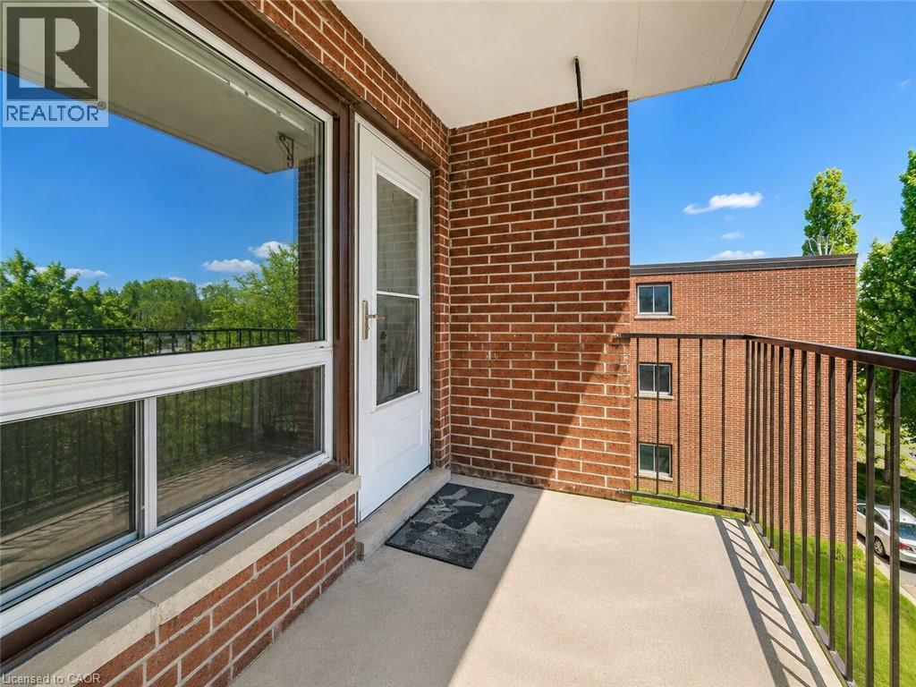 Private balcony with textured flooring, brick exterior, and metal railings - 4 Avalon Place Unit# 303, Kitchener, ON