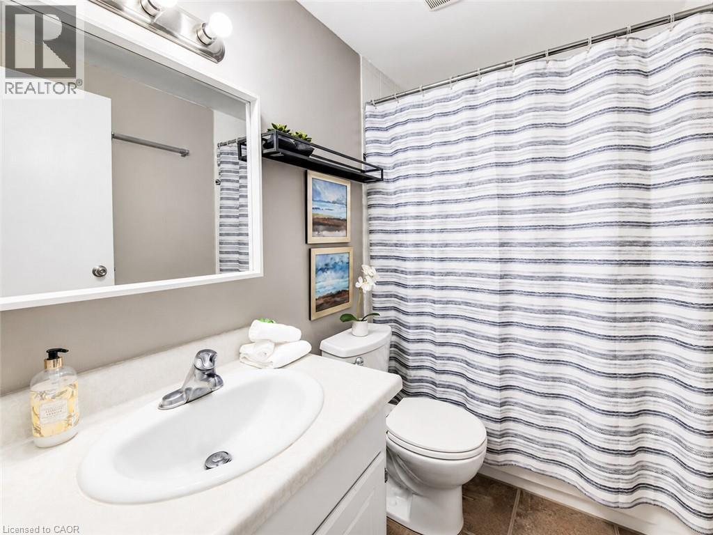 Bathroom featuring a white vanity with integrated sink, chrome faucet, white toilet, and tile flooring - 4 Avalon Place Unit# 303, Kitchener, ON