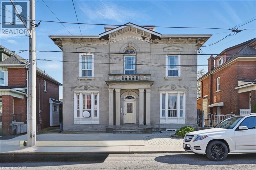 Stone facade with decorative window trim, bay windows, and a portico entrance - 55 Barton Street W, Hamilton, ON