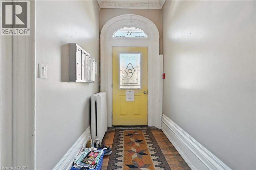 Arched entry door with stained glass insert, decorative transom, and crown molding - 55 Barton Street W, Hamilton, ON