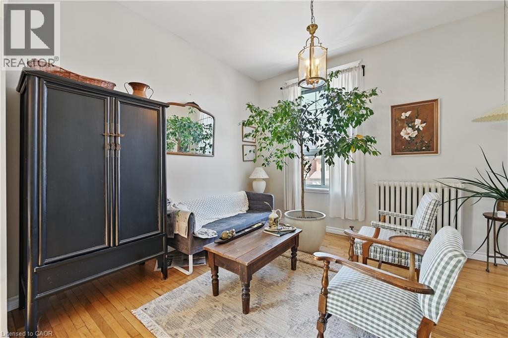 Hardwood flooring, cased window with white drapery, and a classic radiator - 55 Barton Street W, Hamilton, ON