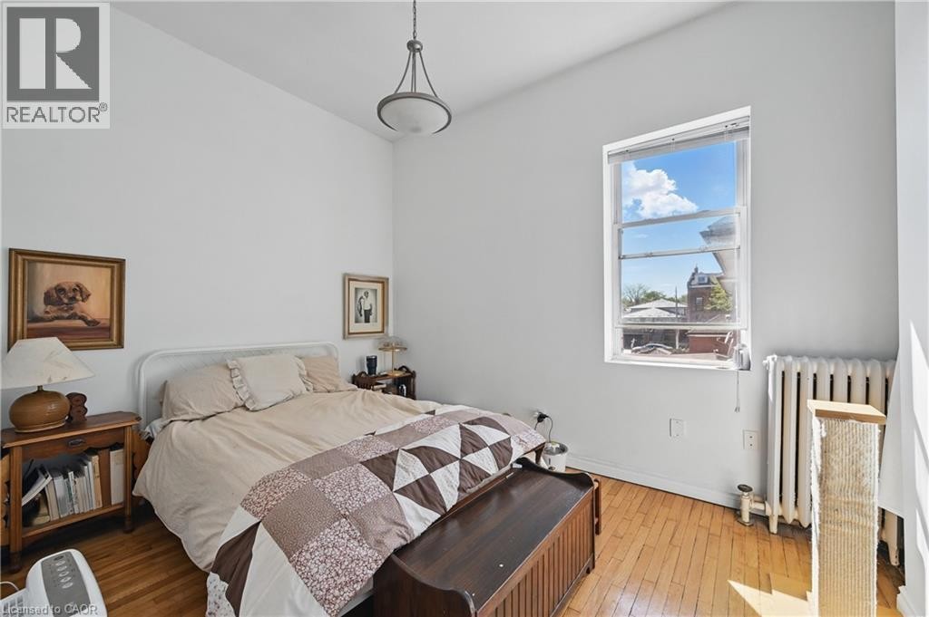 Hardwood flooring, high ceilings, large window, pendant light fixture, and classic radiator - 55 Barton Street W, Hamilton, ON