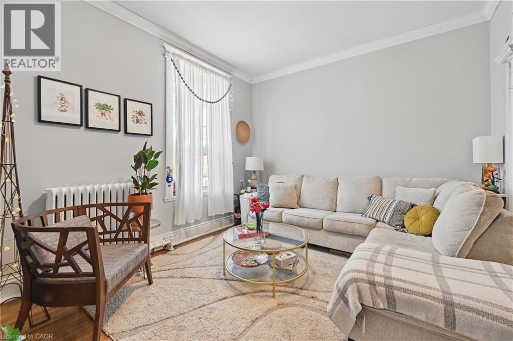 Hardwood flooring, crown molding, a large window, and a cast iron radiator - 55 Barton Street W, Hamilton, ON