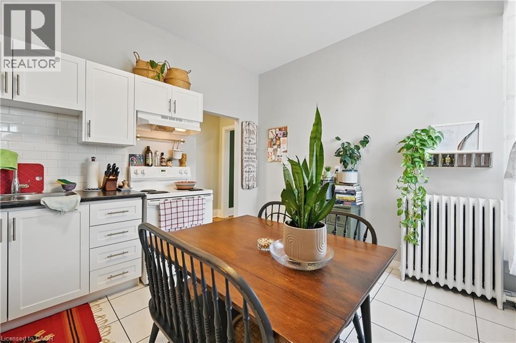 White cabinetry with brushed nickel hardware, subway tile backsplash, white tile flooring, and integrated range - 55 Barton Street W, Hamilton, ON