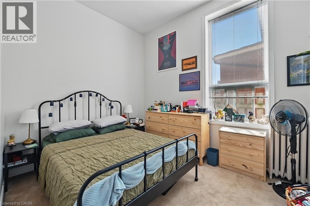 Painted walls, single window with blinds, wood-finish flooring, and a wall-mounted radiator - 55 Barton Street W, Hamilton, ON