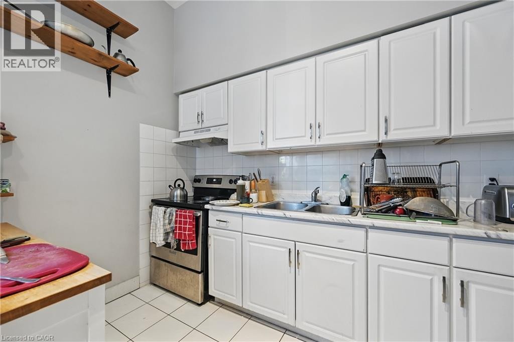 Kitchen featuring white cabinetry, a stainless steel range, a double basin sink, white tile flooring, and white tiled backsplash - 55 Barton Street W, Hamilton, ON