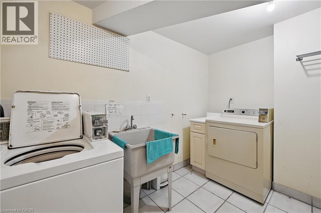 Laundry area featuring a utility sink, tiled flooring, pegboard wall storage, and wall-mounted drying rack - 55 Barton Street W, Hamilton, ON