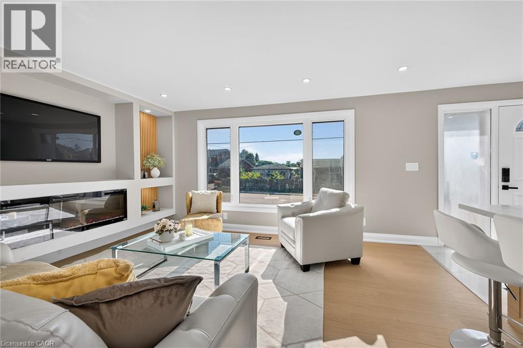 Recessed lighting, wood-finish flooring, built-in shelving, fireplace, and clear glass window - 135 Nugent Drive, Hamilton, ON