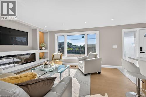 Recessed lighting, wood-finish flooring, built-in shelving, fireplace, and clear glass window - 135 Nugent Drive, Hamilton, ON 
