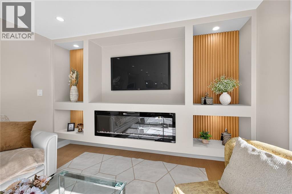 Built-in media center with integrated fireplace, recessed lighting, wood paneling, and shelving - 135 Nugent Drive, Hamilton, ON