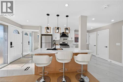 Open-concept kitchen featuring an island with a light wood finish, white countertop, and stainless steel appliances - 135 Nugent Drive, Hamilton, ON 